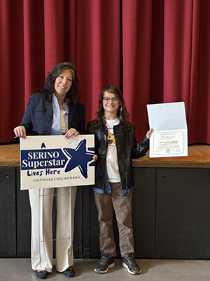 County Executive Sue Serino taking picture with honoree holding certificate and yard sign