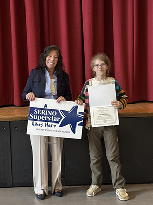 County Executive Sue Serino taking picture with honoree holding certificate and yard sign