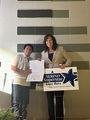 Sue Serino taking picture with honoree with certificate and yard sign