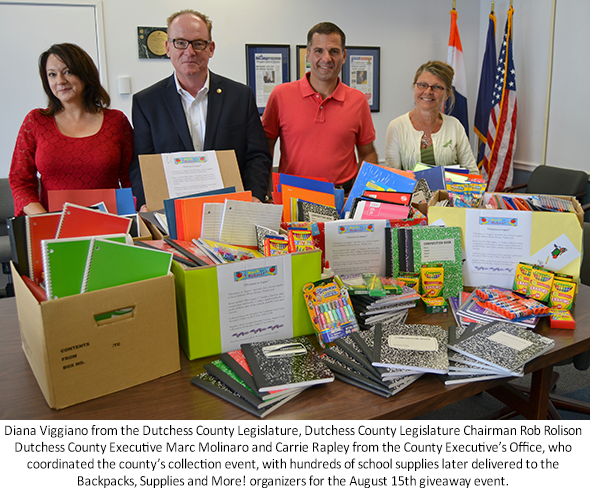 County Executive Molinaro with Chairman Rolison and County employees standing next to school supplies