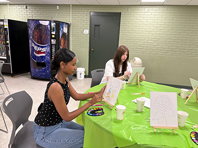 Two people painting pictures at a table