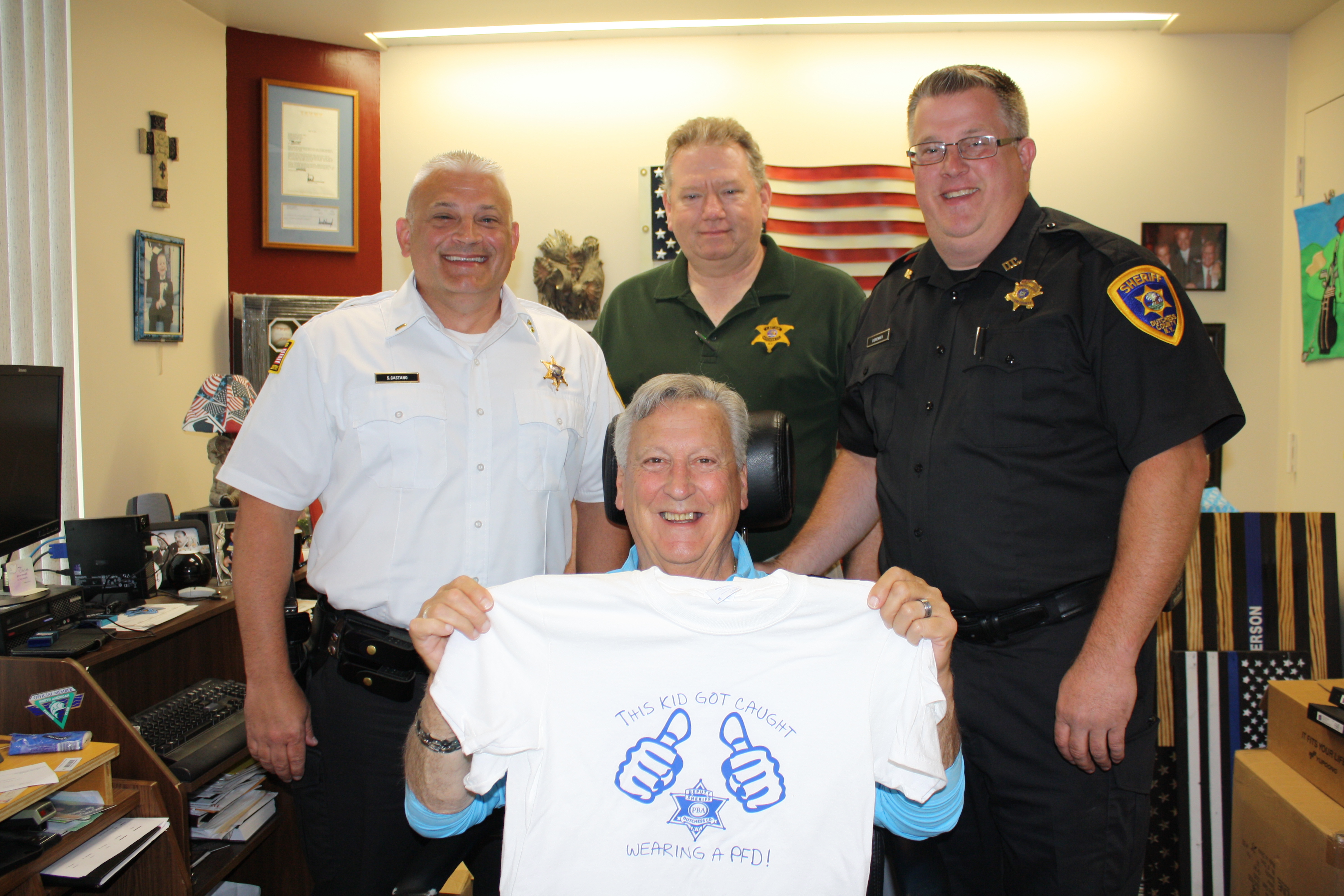 Sheriff Anderson holding up a "this kid got caught wearing a PFD" (Personal Flotation Device)